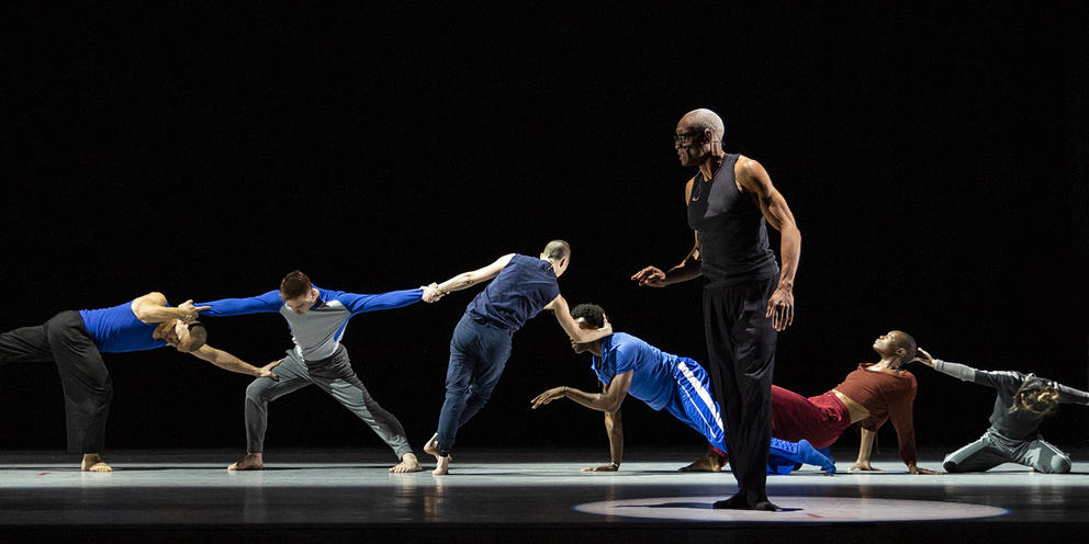 photo of a group of dancers moving on a dark stage