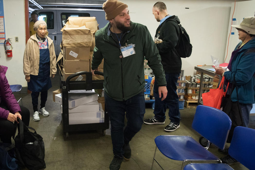 a man wheels a cart into a food bank