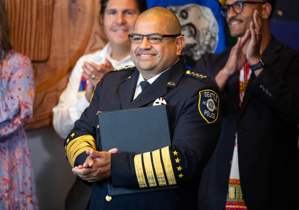 A man in a seattle police chief uniform stands in a conference room