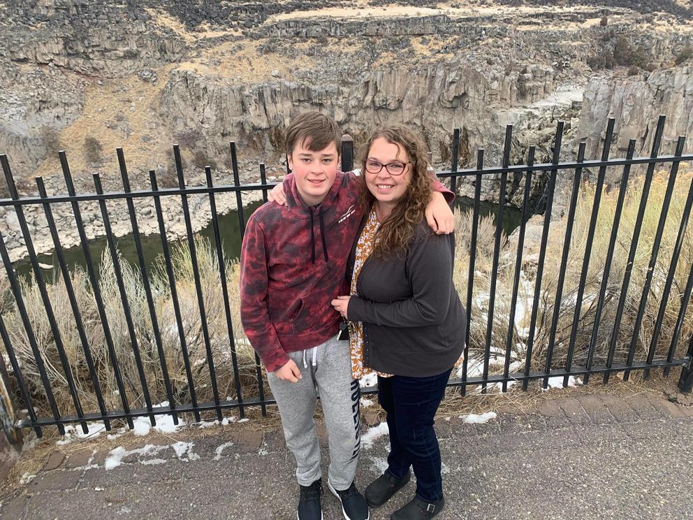 Sally McLaughlin stands with her son Clover outdoors in front of a fence