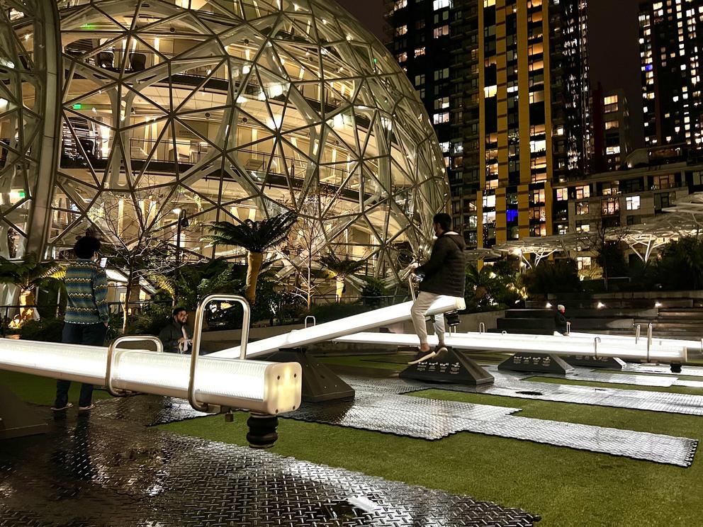 a series of illuminated seesaws near a spherical building