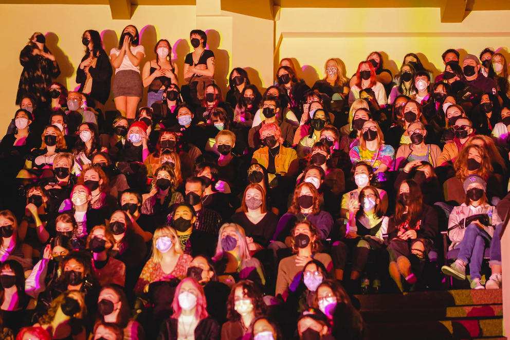 An audience of roughly 50 people wearing masks