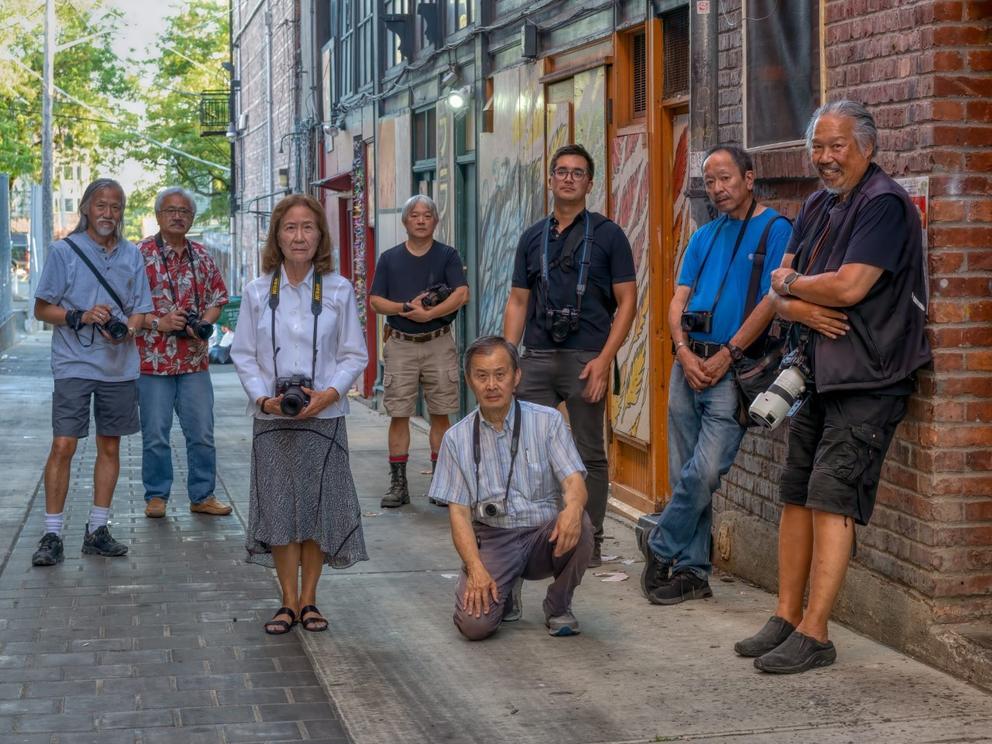 A group of men and women pose for a photo while holding their cameras