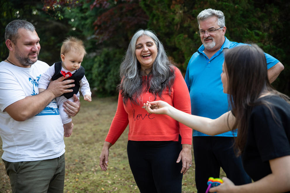 Olena Roze throws leaves to entertain Max as he’s held by his father.