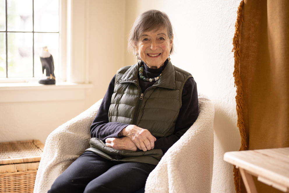 Person in chair with hands folded on lap, window nearby brings soft light in