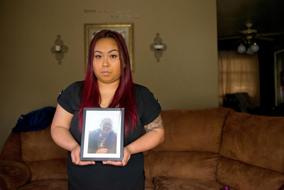 Bopha Khliu poses for a portrait with a picture of her father, Sun Khliu, taken just before his detention, at her home in Portland, Ore.