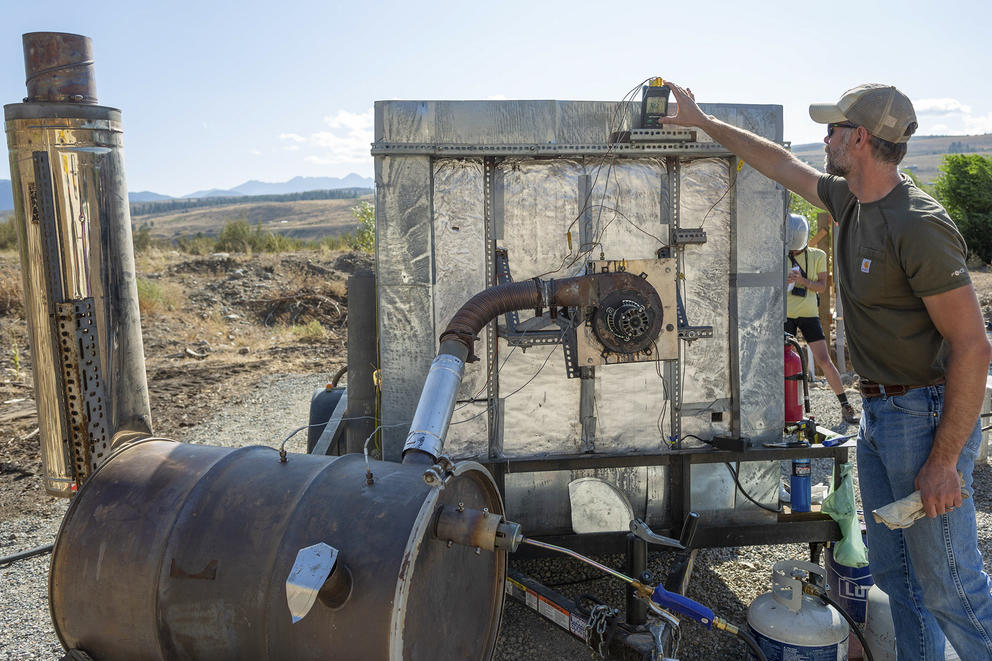 A man adjusts a piece of machinery outside.