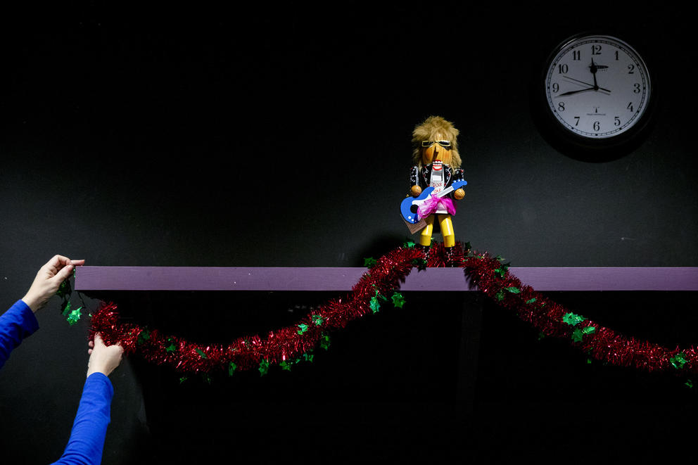 A pair of hands pin up tinsel on a shelf 