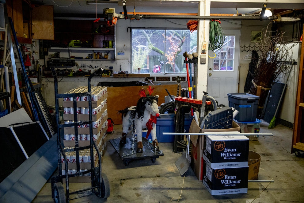 A decorated toy horse and cases of beer in a garage