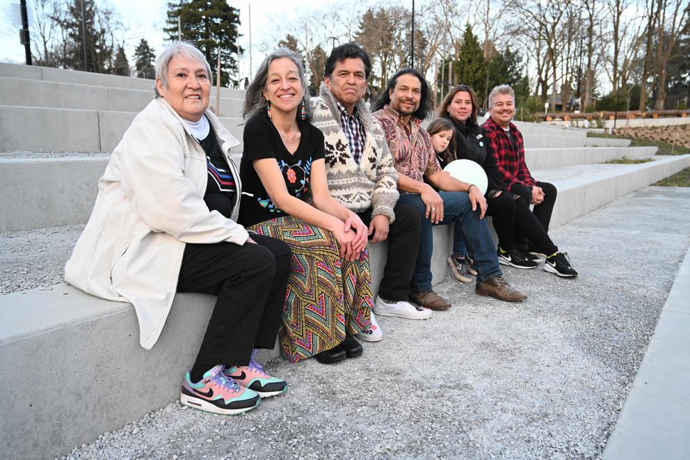 A group of people sitting on concrete steps, looking at the camera