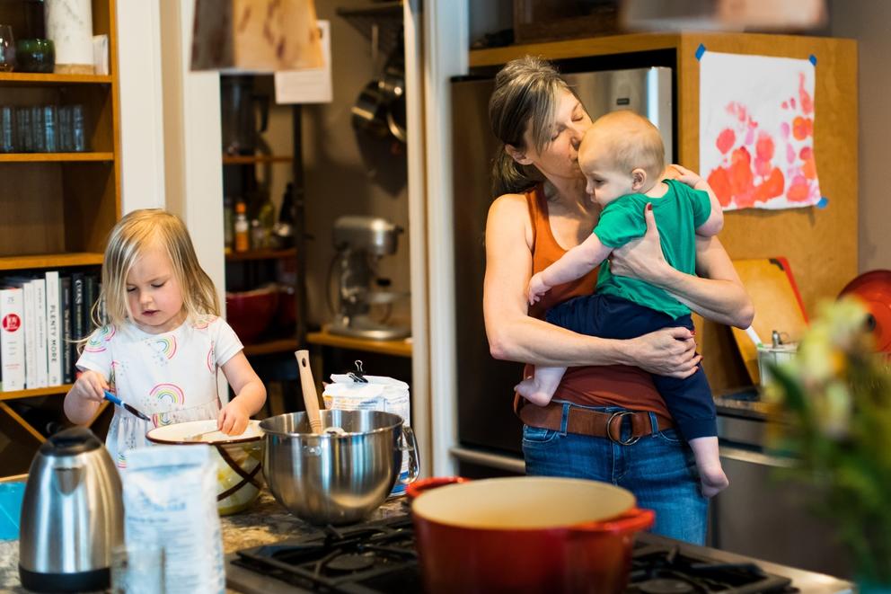 Mom holding one kid with another nearby