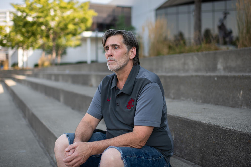 Deryk Terril sits on a set of outdoor stairs with his hands clasped in his lap