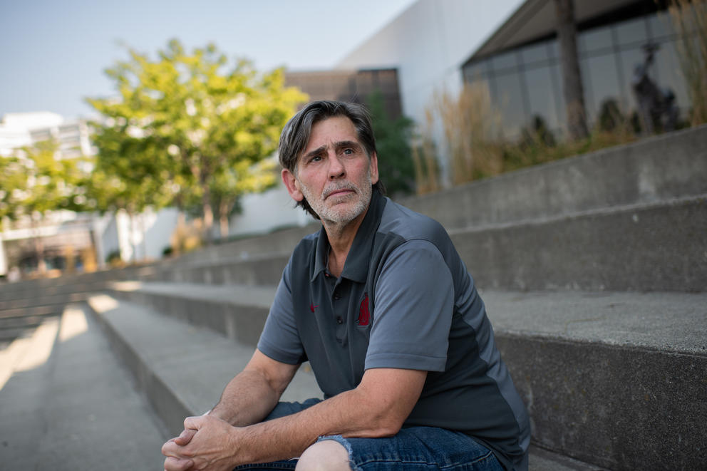 Deryk Terril sits on concrete steps with his hands clasped in his lap