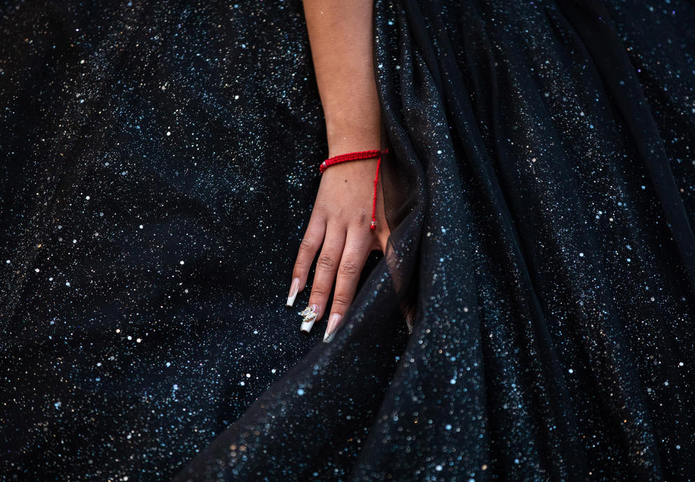 a close up of a woman's hand with painted fingernails on a black sparkly dress