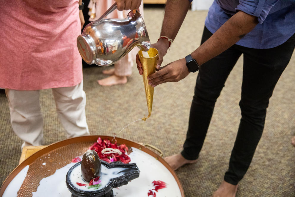 hands hold a golden funnel as milk is poured into in from a silver pitcher