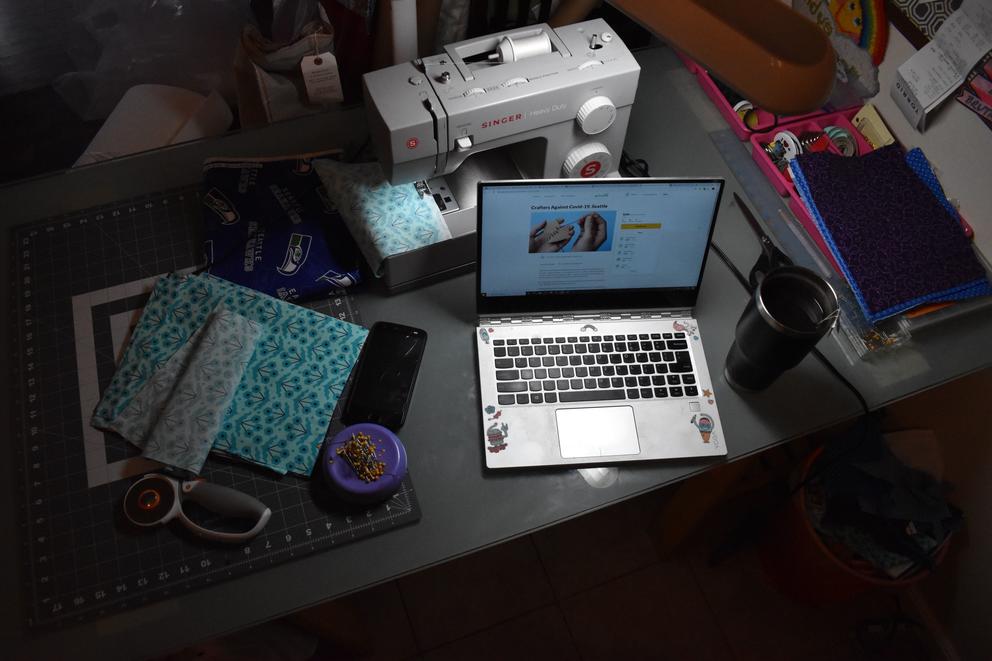 Laptop on desk with crafting materials and sewing machine