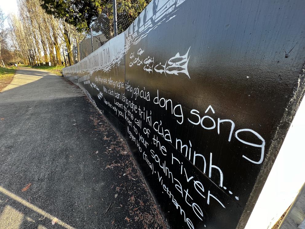 a paved path next to a mural painted with Vietnamese text