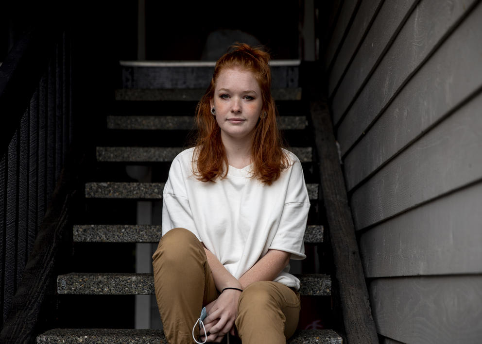 A woman sits outside on stairs