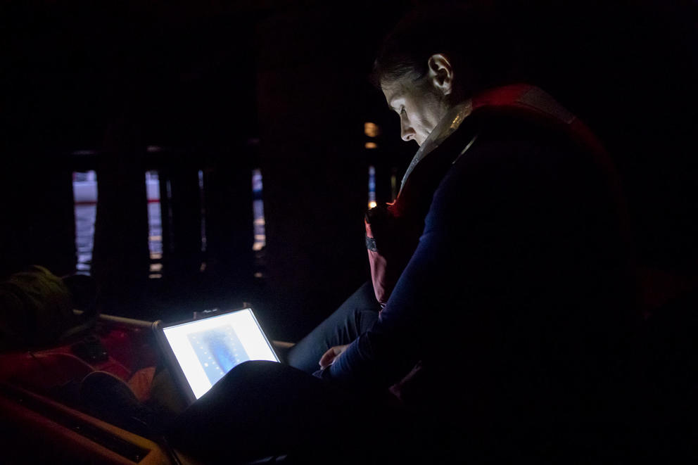 woman looks at computer screen in kayak