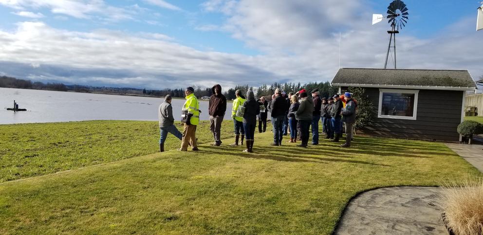 A group of people wearing coats stand near the river