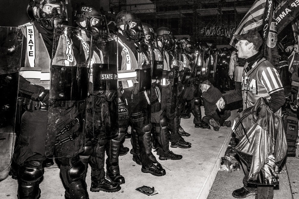 A row of police officers is seen here in a black and white photo taken when it is dark