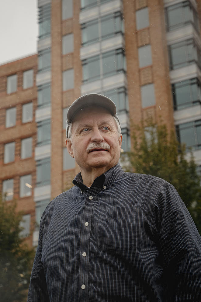 Man stands in front of tall brick building