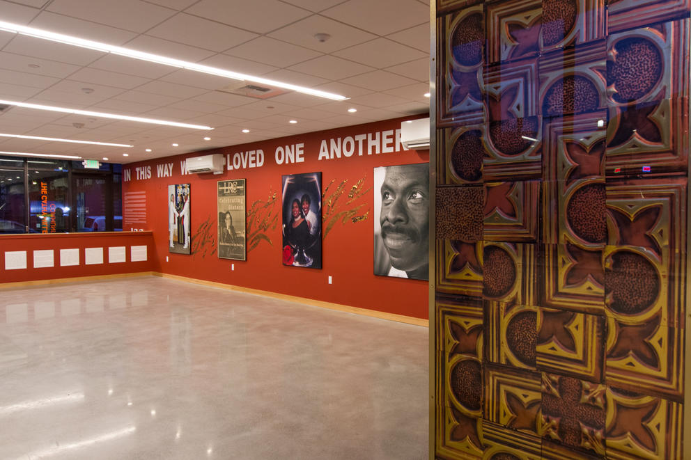 Room with large white table and red walls featuring text and archival photos of people