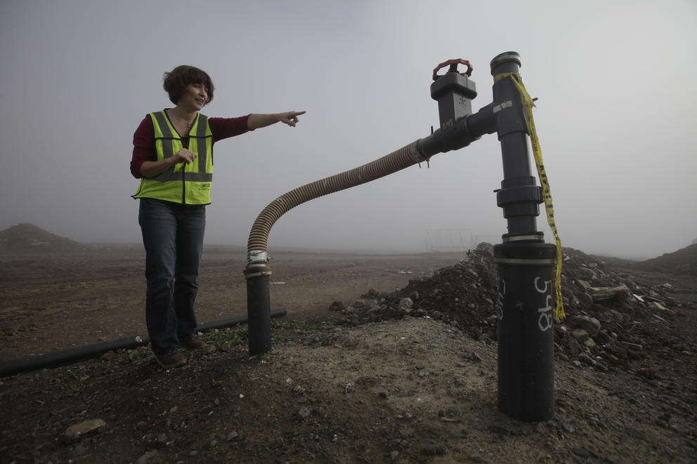 Landfill manager standing near a pump bringing up methane gas.