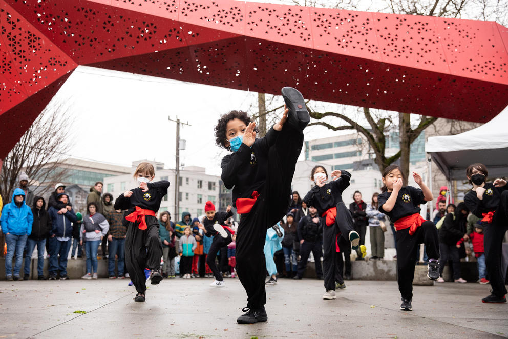 Kids do a martial arts demonstration under a red archway