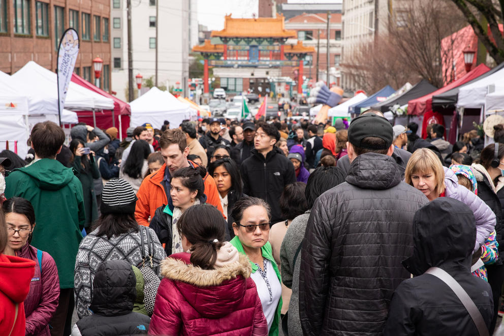 A street crowded with people with a traditional Chinese archway in the background