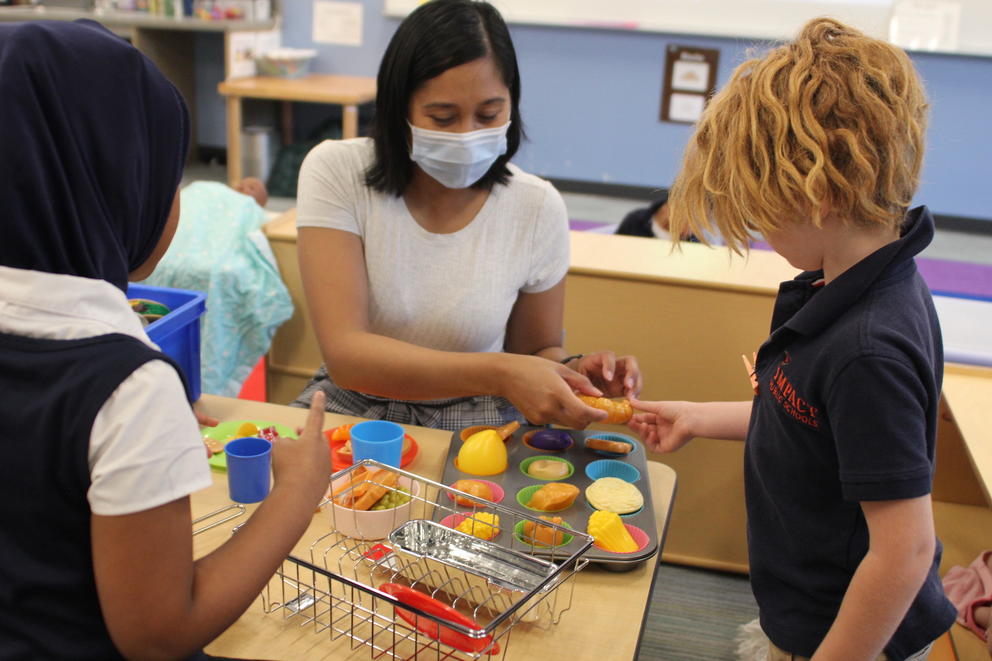 A teacher sits at a desk with a small group of students