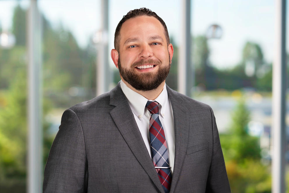 Summit Pacific CEO Josh Martin poses for a photo in front of a window with trees in the background.