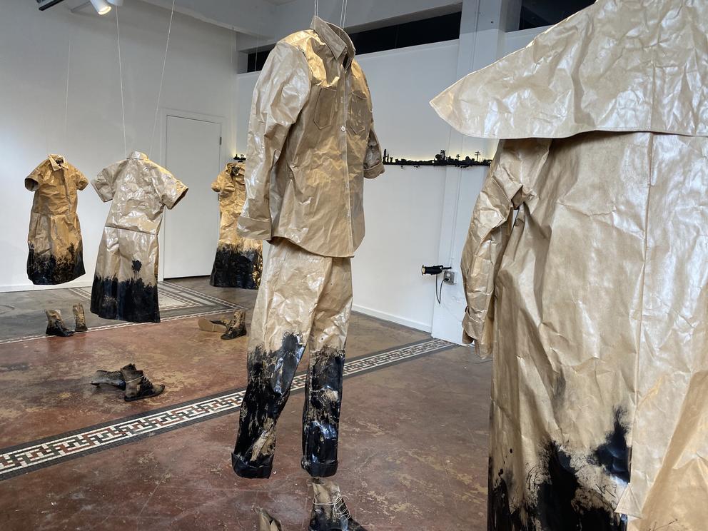 Brown clothing made from crumpled paper, uniforms that hang like ghosts in a gallery