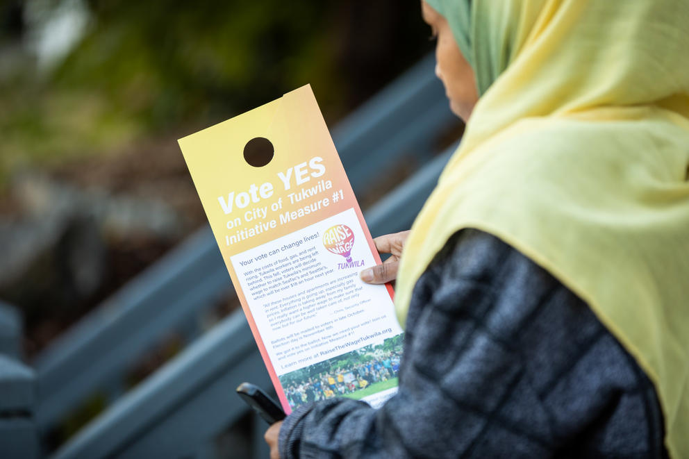 Picture of Tukwila resident looking at flier for minimum wage proposal on the election ballot