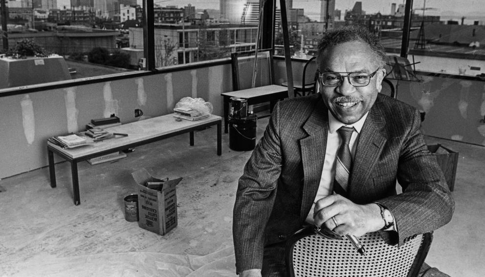 vintage black and white photo of a man in a suit sitting in a partially completed room