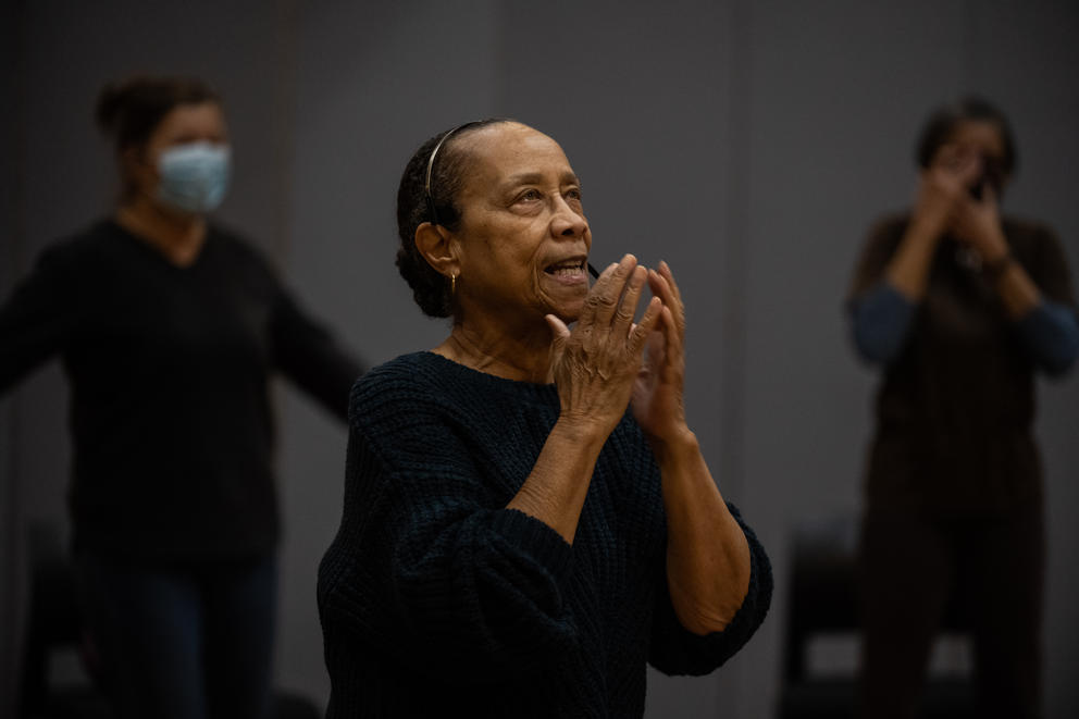 Edna Daigre holds her hands near her face and gazes upward