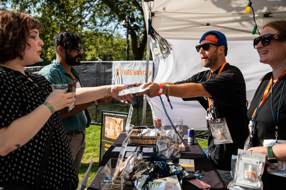 Person in a tent hands something to person on the left