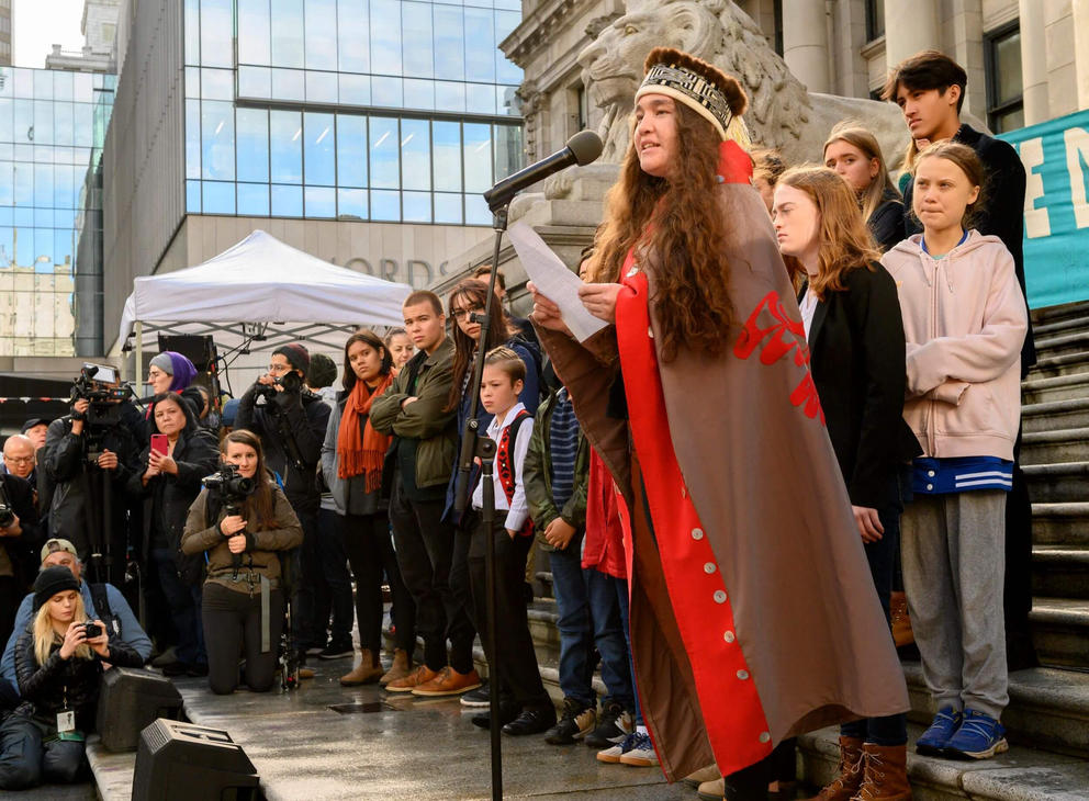 Activist Haana Edenshaw gives a speech flanked by young climate activists