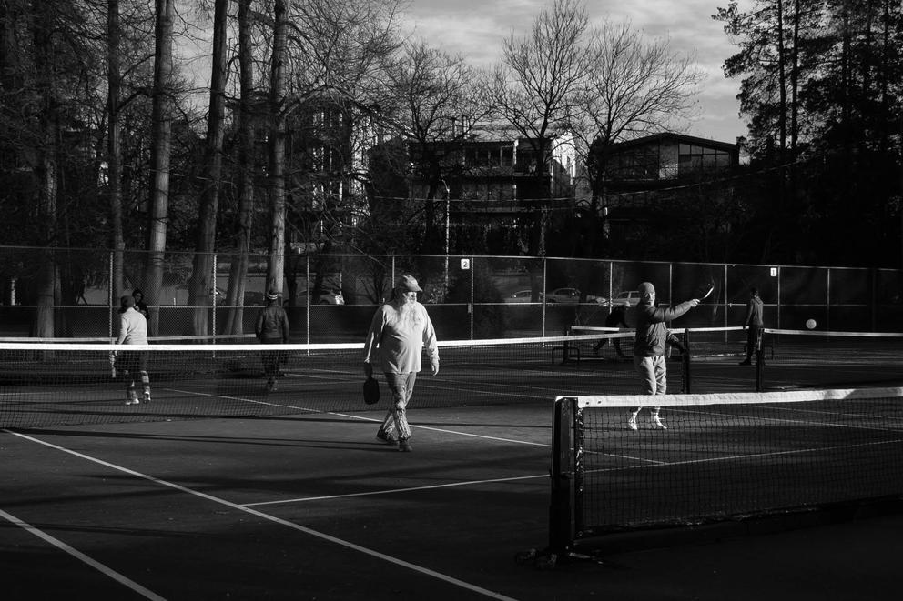 A wide shot of people playing pickleball on an outdoor court - black and white