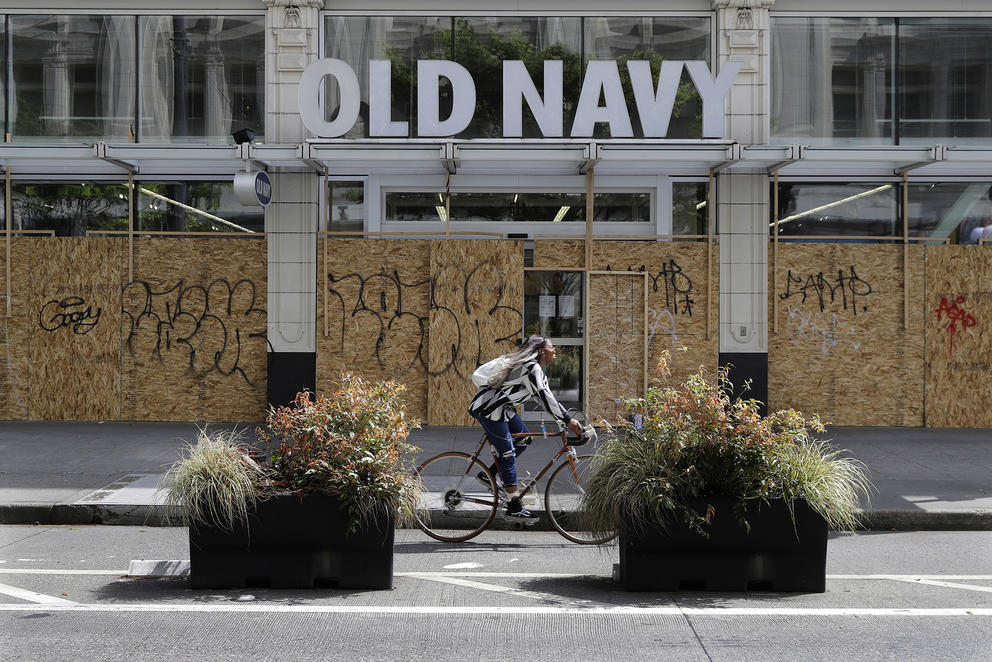 Person rides past a boarded up and closed Old Navy clothing store