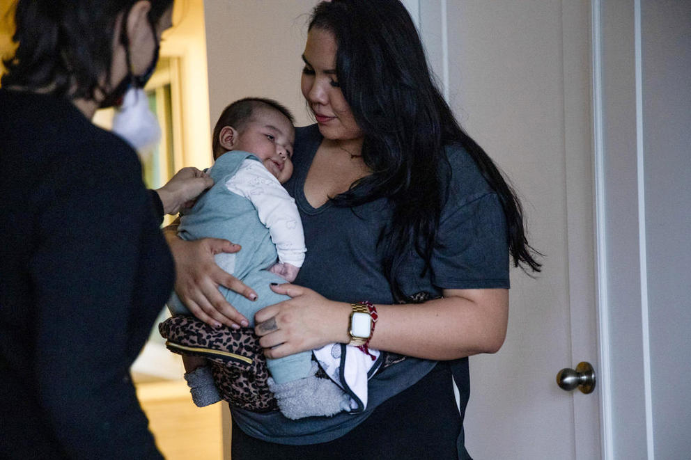 Starr Warner holds her baby facing Cassandra Miles