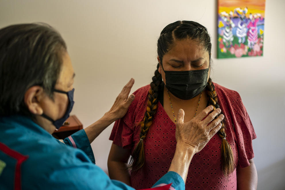 Elder “Mona” Ramona Ahto holds her hands over Terri Claw as they pray