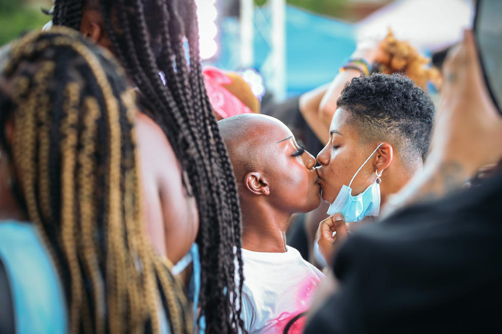 Sydney Menjivar pulls down Jaylynn Malone's blue mask as they share a kiss in a crowd of people