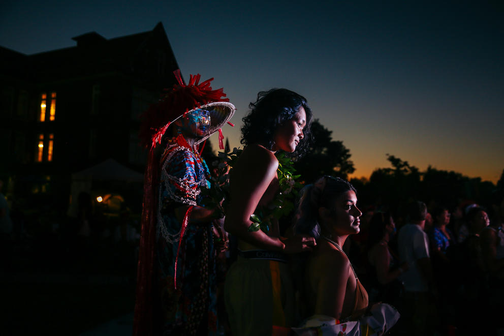 A faint orange glow lights the evening sky as three figures stand together in a sliver of light