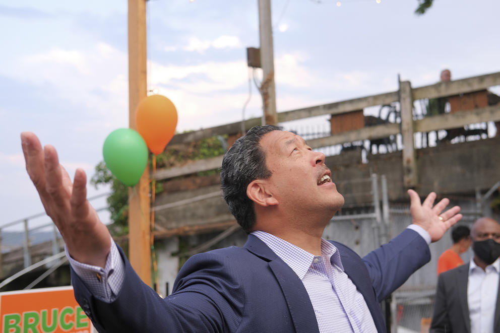 Bruce Harrell gazes up at the sky as it begins to rain with his arms out wide and palms facing up