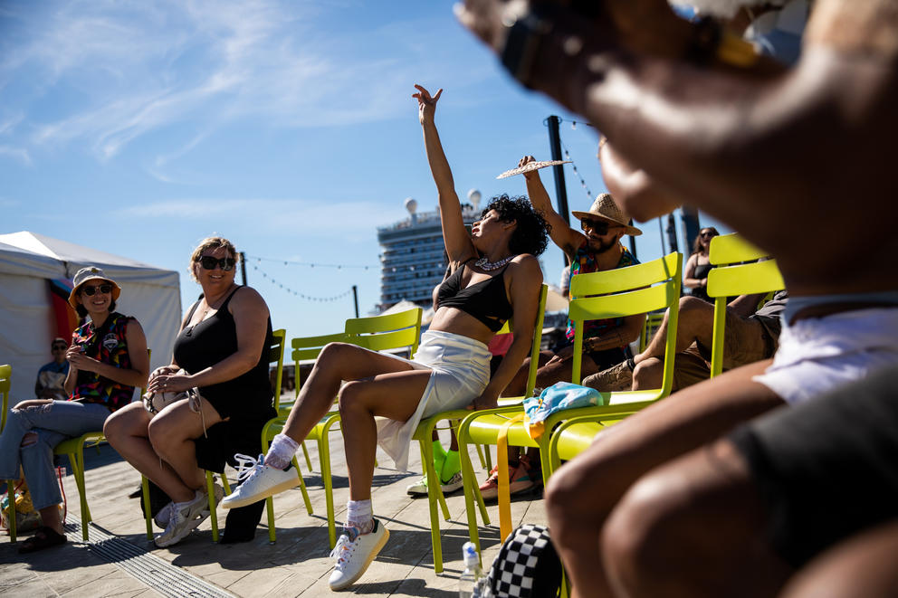 Stephy Styles jumps into the crowd during her performance, she is outside and leaned back with her arm up in a yellow folding chair.