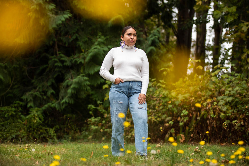 A woman poses in a field surrounded by dandelions