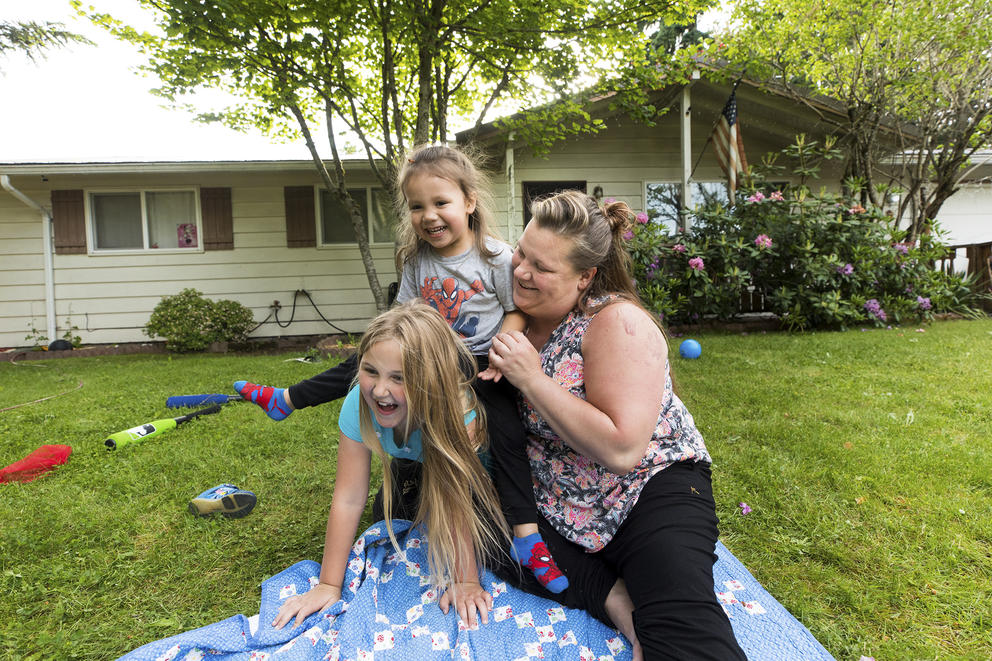 Woman and children play in front of house