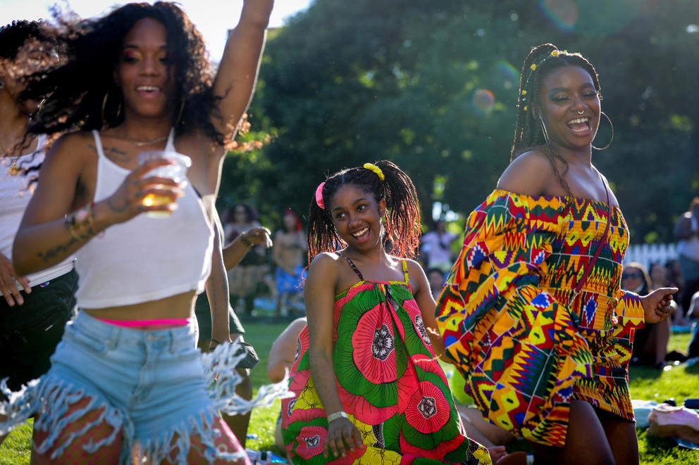 Three people dance in colorful clothes