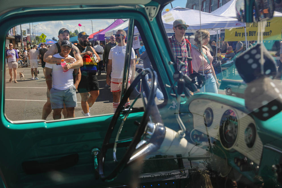 people stroll down a street and are framed in a car window